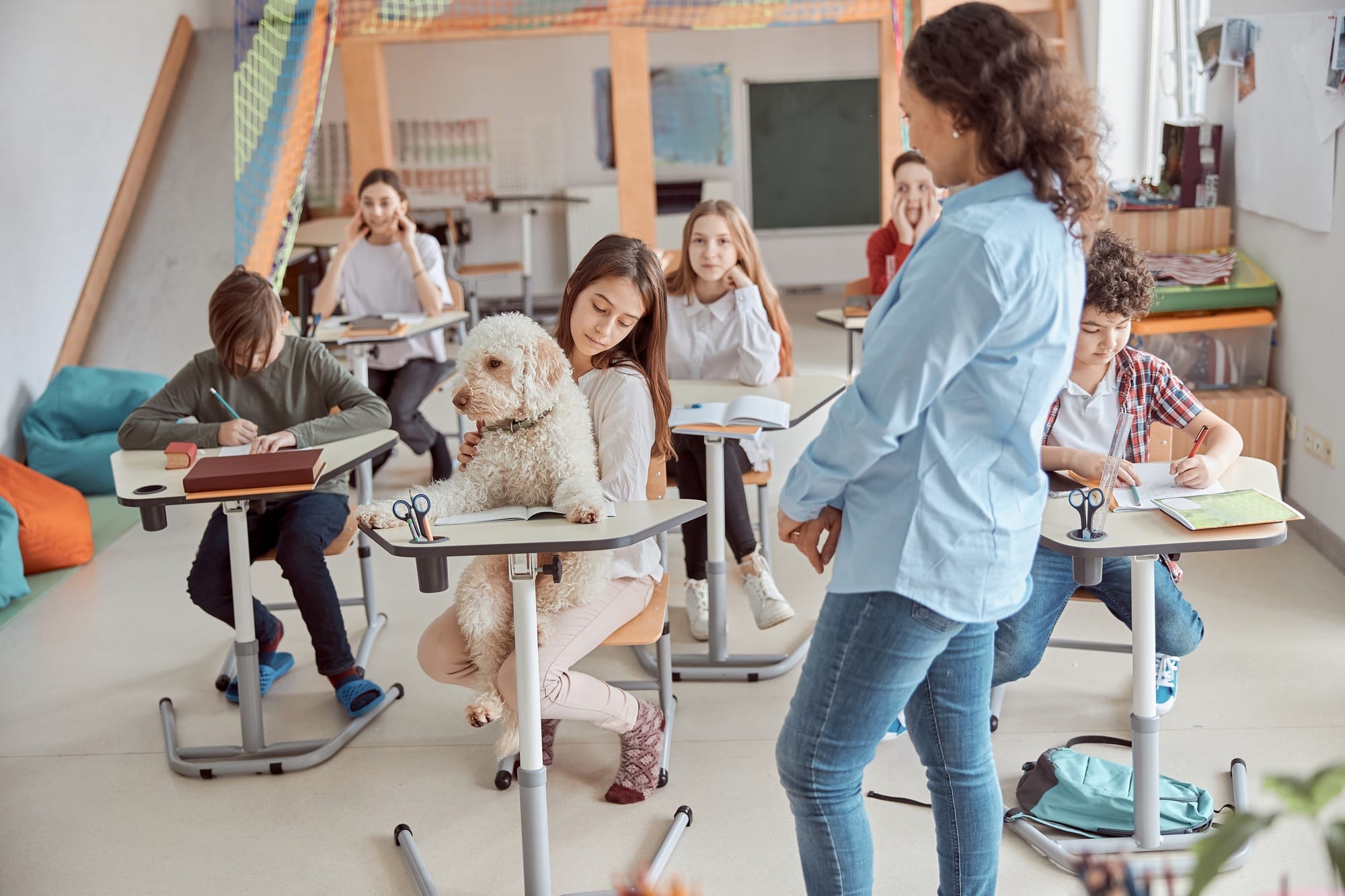 Happy mixed kid pupils in elementary school lesson with a dog in center